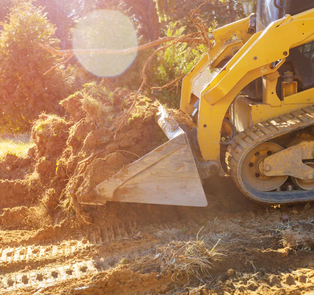 mini bulldozer working with earth soil while doing landscaping works on construction site